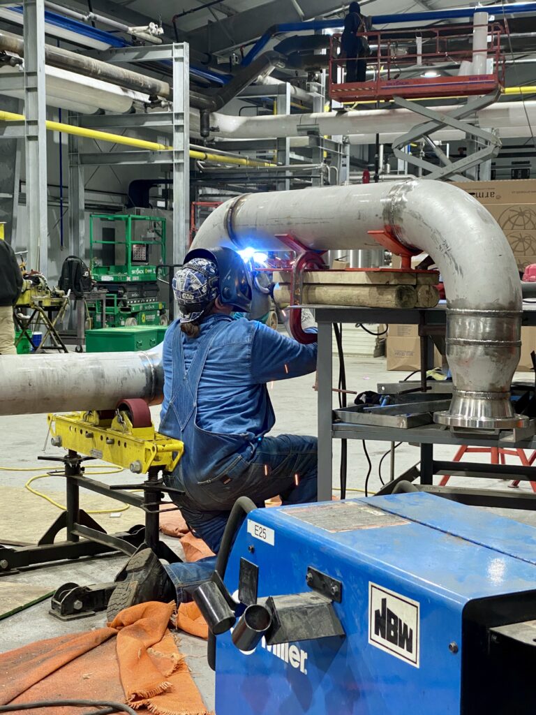 A worker welding a pipe. NBW Inc.